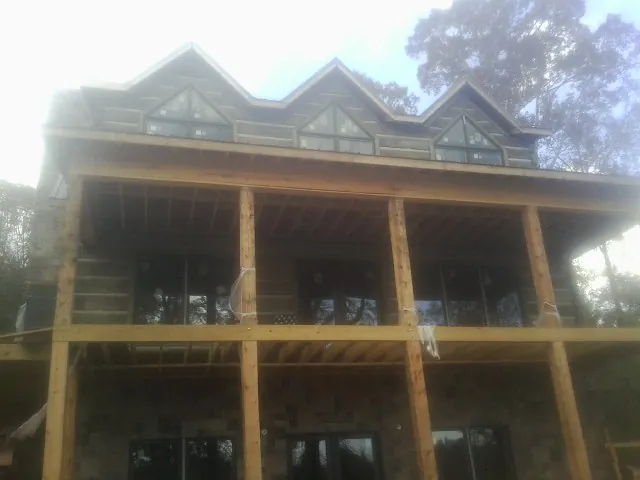 Dormers and porch framing on a large log home under construction — Roof Coating work by our crew in Queen Anne