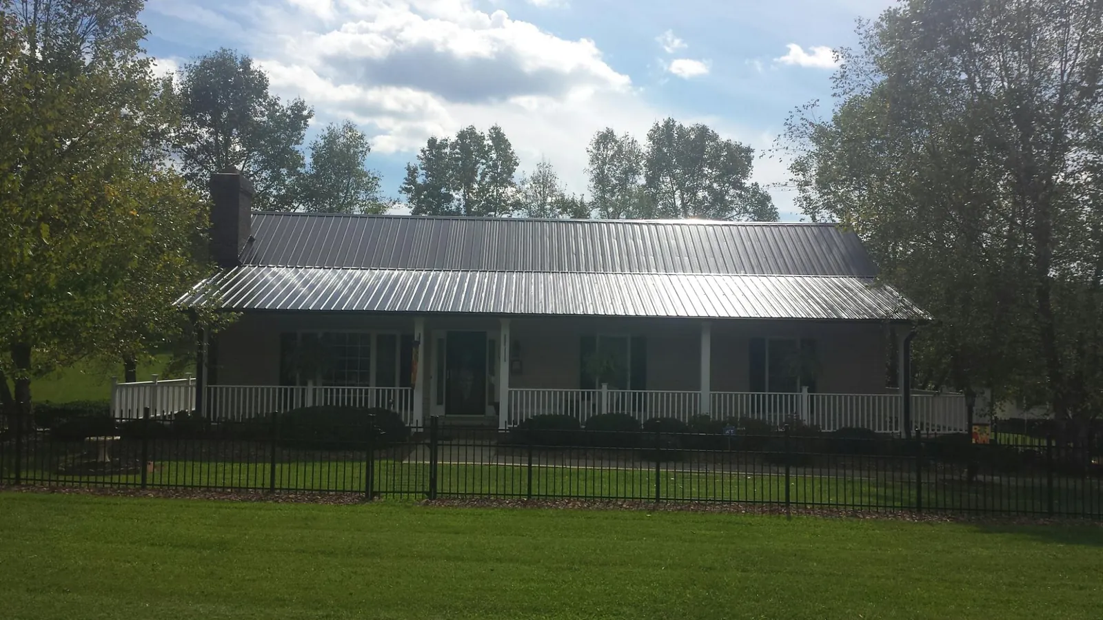 Gray metal roof on a brick ranch with a full width front porch — Gutter Guard Installation work by our crew in Queen Anne