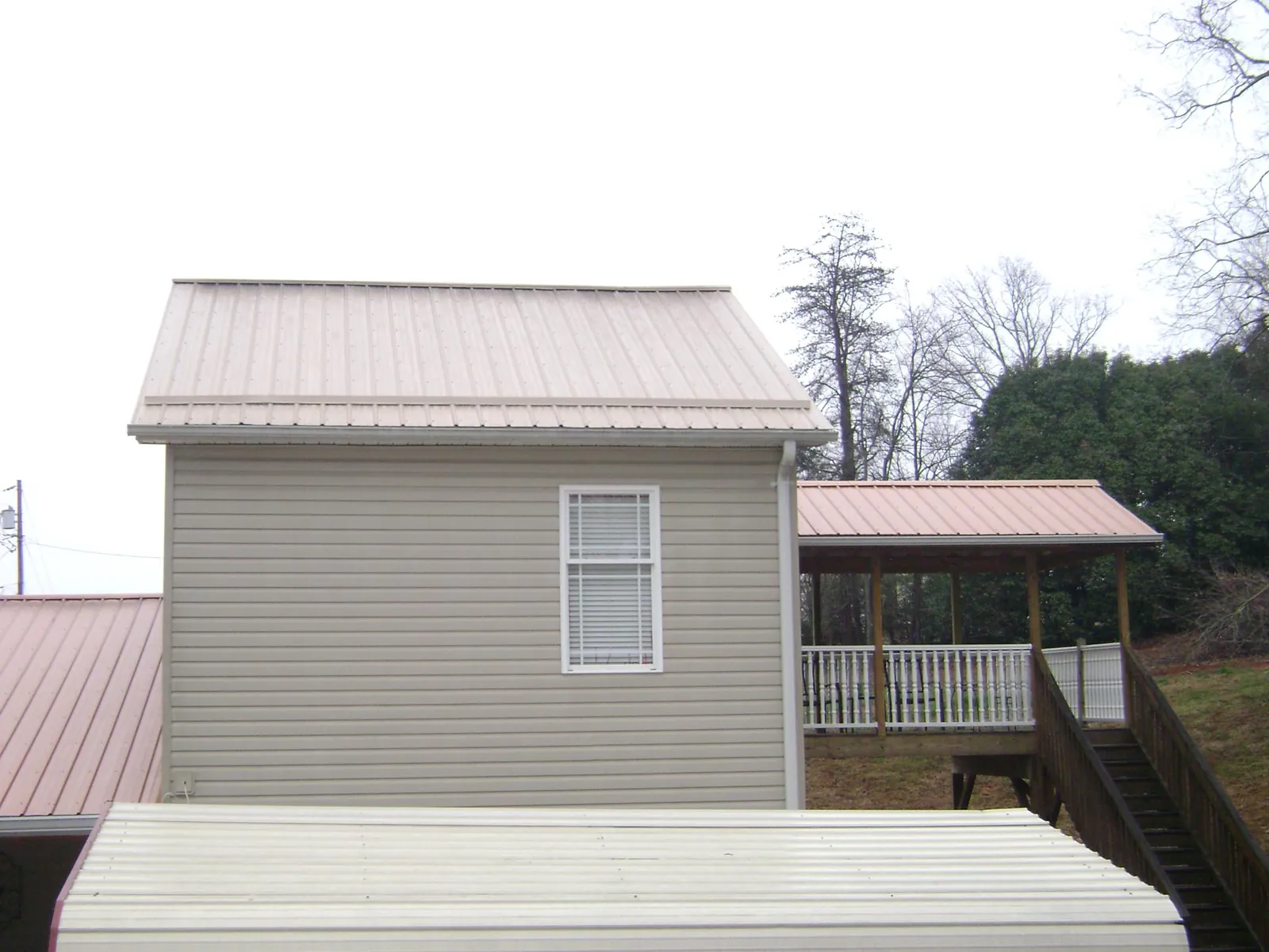 Tan metal roofs on a two story addition and attached porch, from a Roof Replacement job in Queen Anne